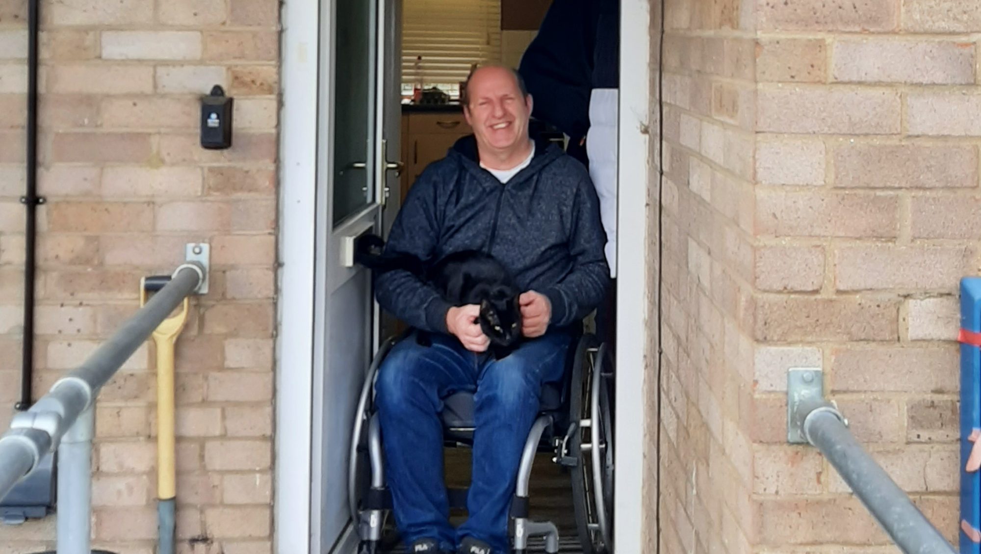 Smiling man in a wheelchair holding a cat
